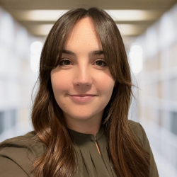 A caucasian woman with brown hair and curtain bangs wearing an olive green top
